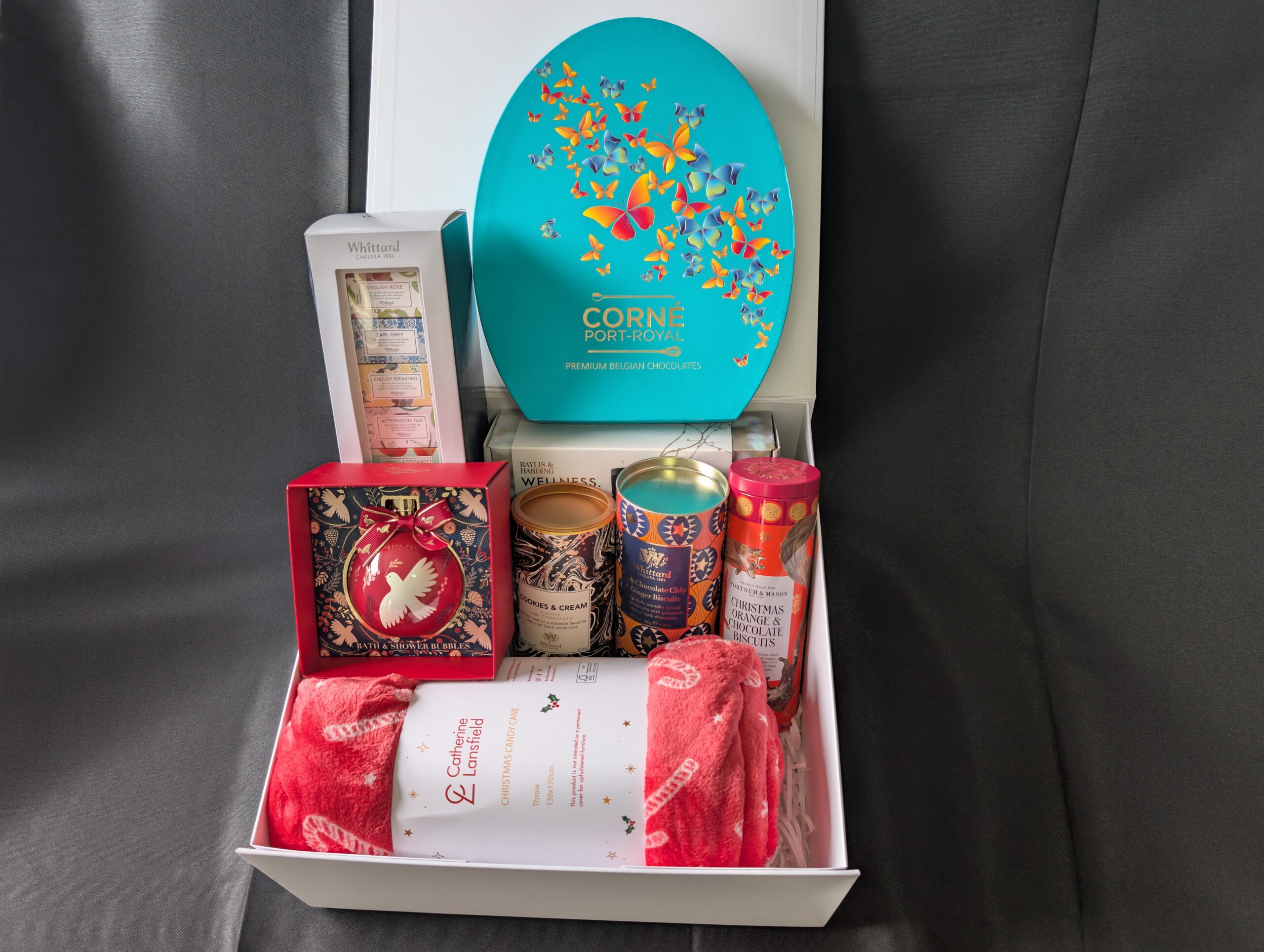 Luxury festive gift hamper flatlay with chocolates, wine, and ribbons