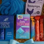 Relax and Indulge Pamper Gift Hampers – Relaxation and chocolate gift set with tea, bath bar, and self-care treats beautifully wrapped in blue ribbon.